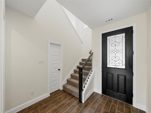 entryway featuring wood tiled floor, visible vents, stairway, and baseboards