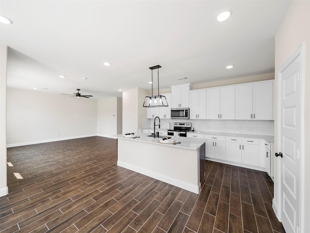 kitchen featuring stainless steel appliances, wood tiled floor, a sink, and decorative backsplash