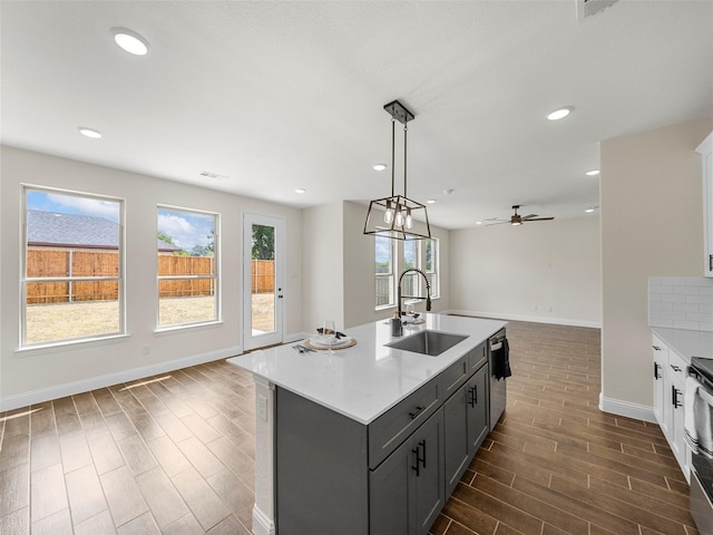 kitchen with wood tiled floor, open floor plan, a sink, and light countertops