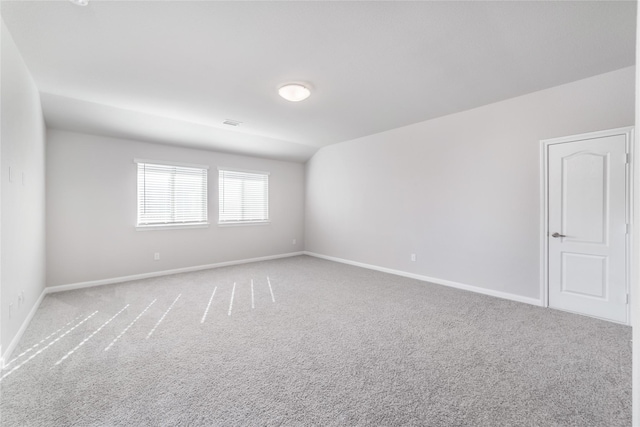 spare room with carpet flooring and vaulted ceiling