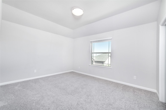 carpeted spare room with lofted ceiling