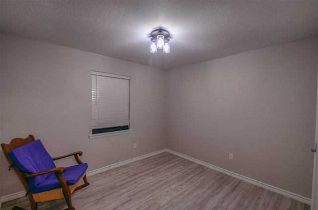 unfurnished room with a textured ceiling and light hardwood / wood-style floors