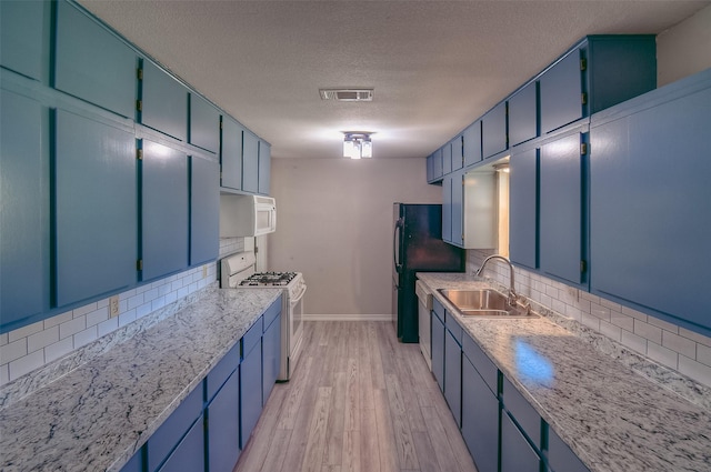 kitchen with blue cabinetry, a textured ceiling, white appliances, and tasteful backsplash