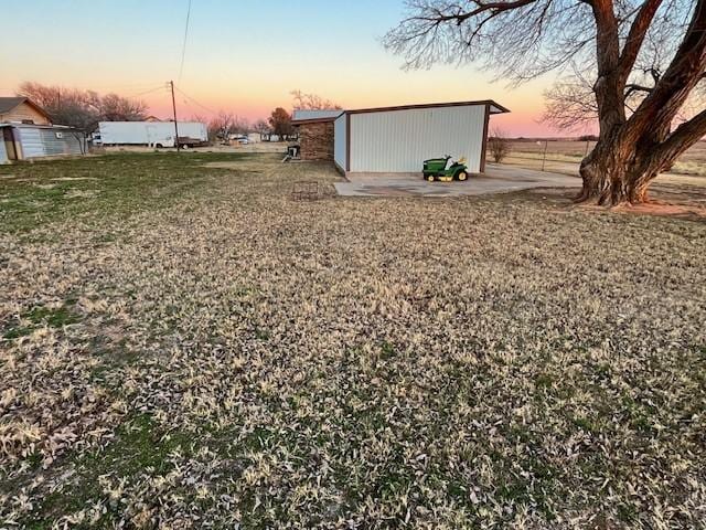 yard at dusk featuring a garage and an outdoor structure