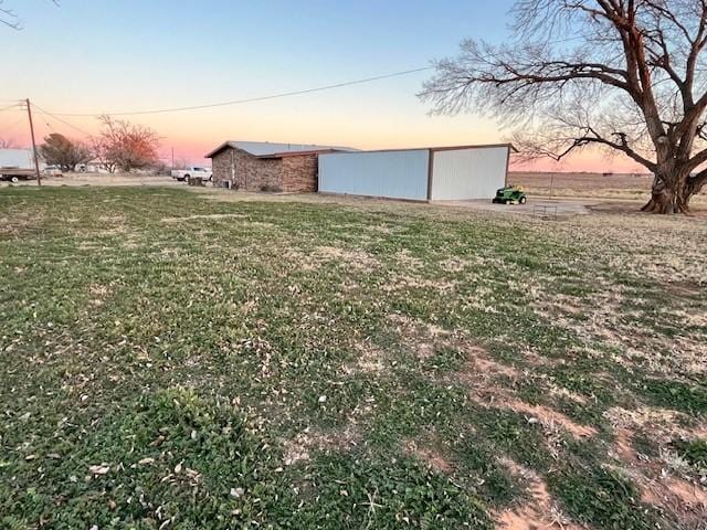 yard at dusk featuring an outbuilding