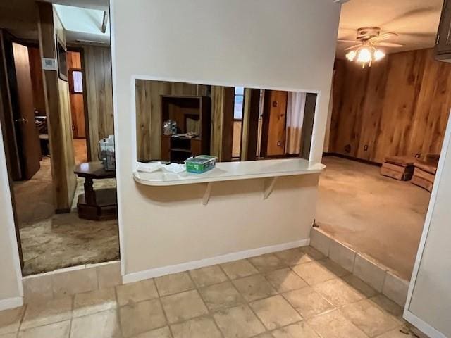 interior space with ceiling fan, light carpet, and wooden walls