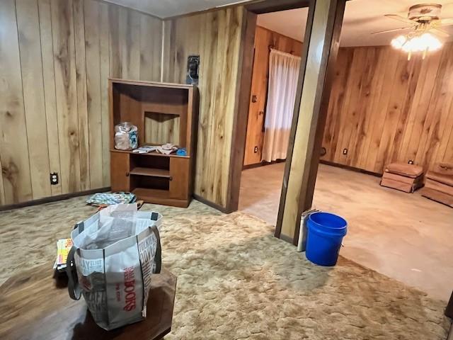 miscellaneous room featuring ceiling fan, light colored carpet, and wooden walls