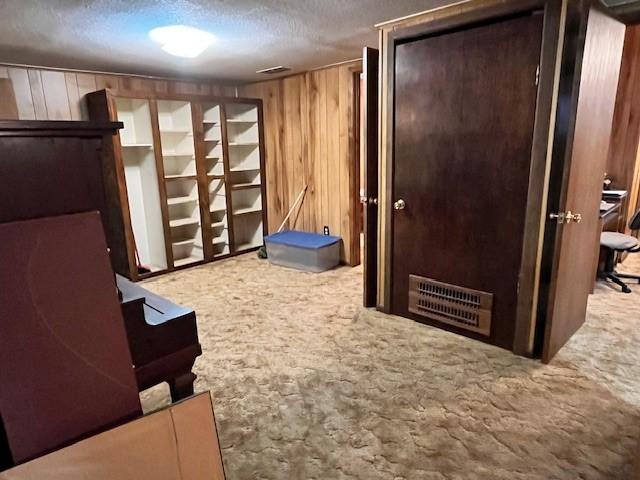 carpeted bedroom with a textured ceiling and wooden walls