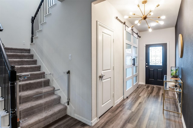 entryway with dark hardwood / wood-style flooring, a barn door, and a notable chandelier