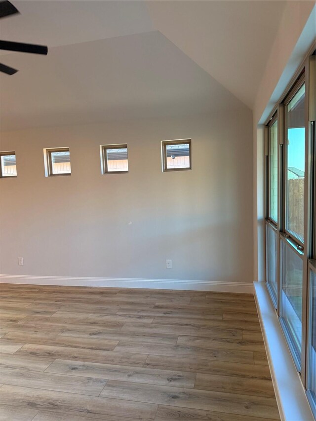 unfurnished living room featuring ceiling fan with notable chandelier, light hardwood / wood-style flooring, a fireplace, and vaulted ceiling