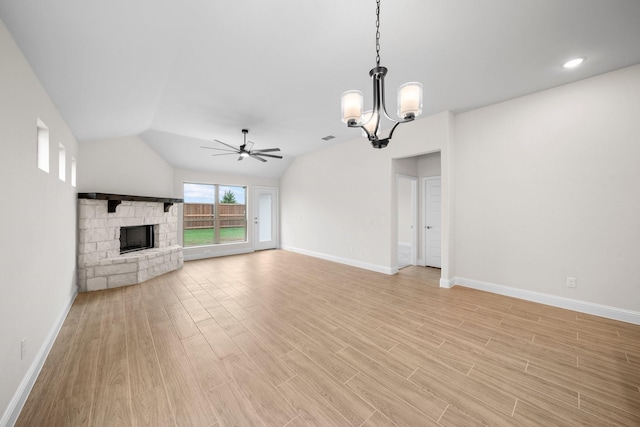 unfurnished living room featuring a fireplace, ceiling fan with notable chandelier, and vaulted ceiling