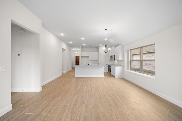 unfurnished living room with sink, light hardwood / wood-style floors, and an inviting chandelier