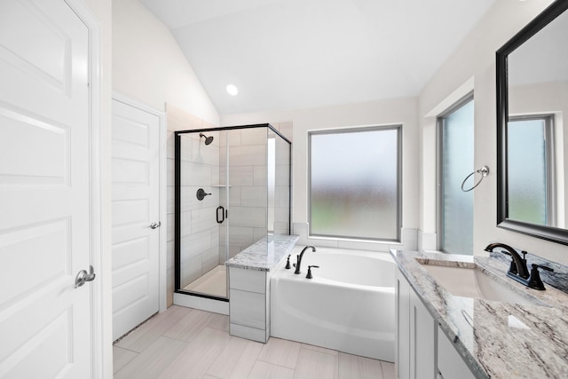 bathroom featuring vanity, independent shower and bath, and vaulted ceiling