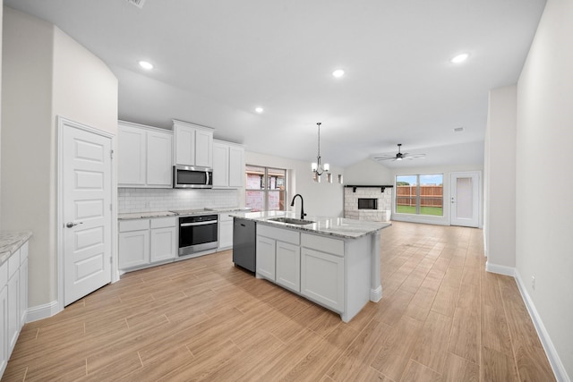 kitchen with white cabinets, sink, stainless steel appliances, and vaulted ceiling