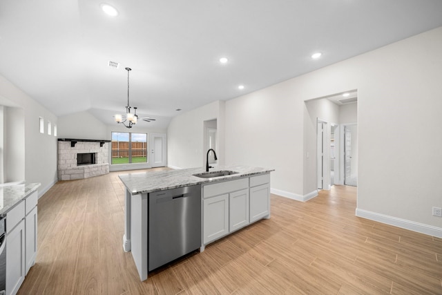 kitchen featuring dishwasher, lofted ceiling, sink, a fireplace, and an island with sink