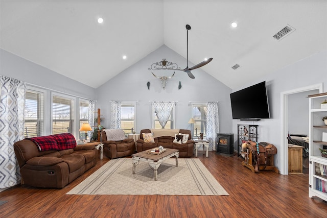 living room featuring high vaulted ceiling, a wood stove, ceiling fan, and dark wood-type flooring