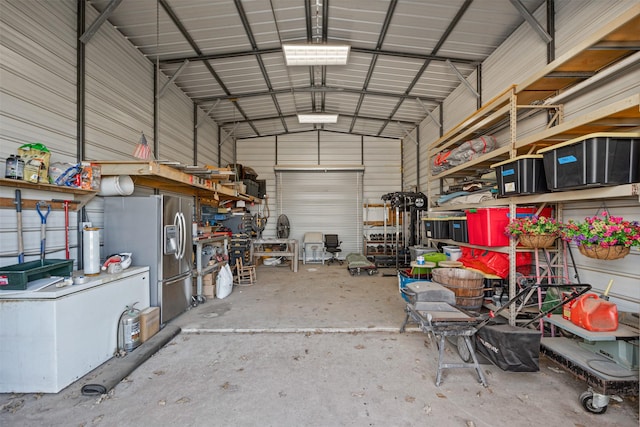 garage with stainless steel refrigerator with ice dispenser and a workshop area