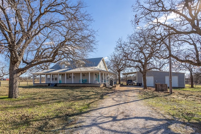 view of front of property featuring covered porch, a garage, a carport, and an outdoor structure