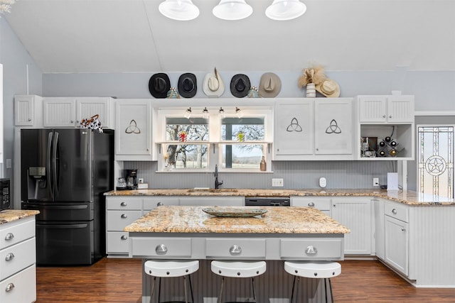 kitchen featuring white cabinetry, sink, a center island, light stone countertops, and stainless steel fridge