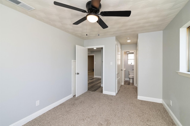 unfurnished bedroom with ceiling fan, light colored carpet, and connected bathroom