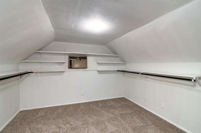 spacious closet with carpet flooring, a wall mounted air conditioner, and lofted ceiling