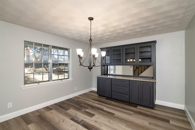 unfurnished dining area with dark hardwood / wood-style floors and an inviting chandelier