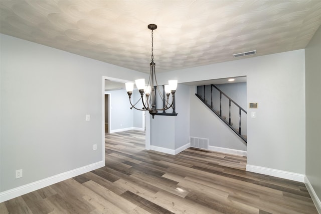 unfurnished dining area with a chandelier and hardwood / wood-style flooring