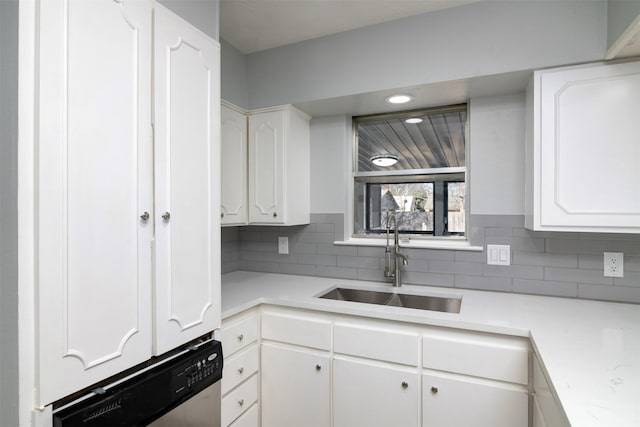 kitchen with tasteful backsplash, white cabinetry, stainless steel dishwasher, and sink