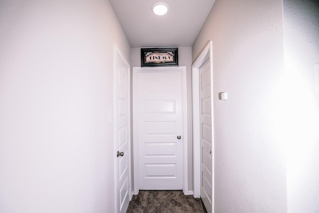 corridor featuring dark colored carpet