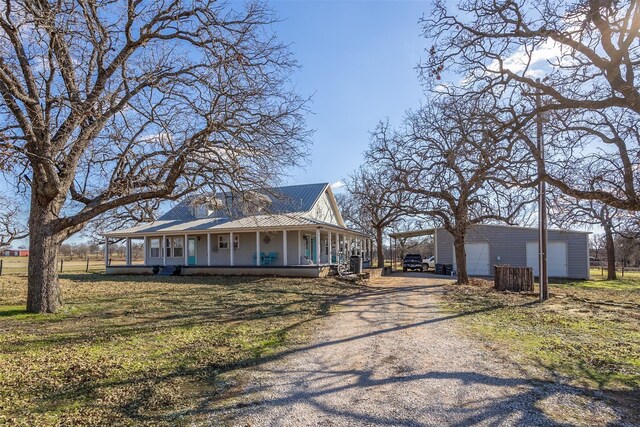 farmhouse featuring covered porch, an outbuilding, and a garage