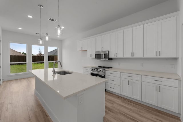 217 Rosemary Dr, Azle, TX 76020 - kitchen with a sink, appliances with stainless steel finishes, light wood finished floors, white cabinets, and a kitchen island with sink