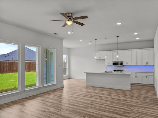 217 Rosemary Dr, Azle, TX 76020 - kitchen featuring stainless steel microwave, a sink, white cabinets, hanging light fixtures, and recessed lighting