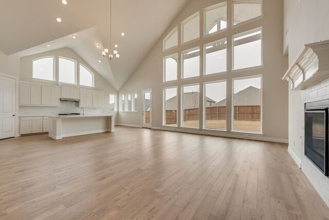 1224 Calebria Way, Fate, TX 75087 - unfurnished living room featuring high vaulted ceiling, a glass covered fireplace, recessed lighting, light wood-type flooring, and baseboards