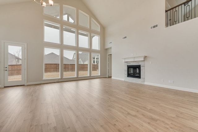 1224 Calebria Way, Fate, TX 75087 - unfurnished living room featuring high vaulted ceiling, light wood finished floors, baseboards, and a glass covered fireplace