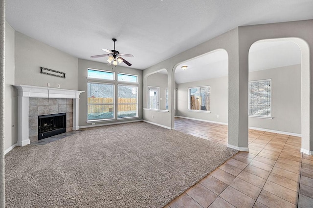 unfurnished living room featuring plenty of natural light, tile patterned flooring, a fireplace, and carpet flooring