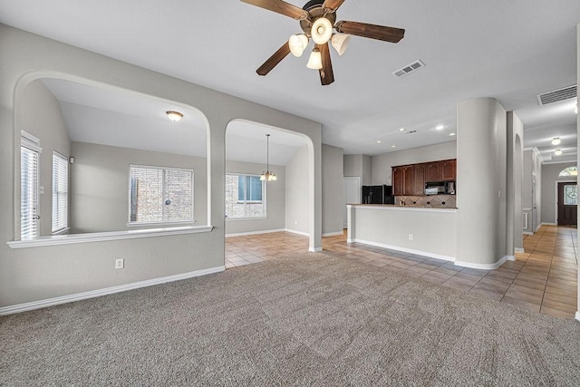 unfurnished living room with light carpet, light tile patterned floors, a healthy amount of sunlight, and visible vents