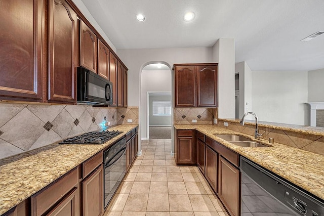 kitchen featuring light tile patterned floors, light stone counters, a sink, visible vents, and black appliances