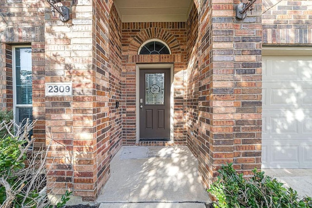 property entrance with a garage and brick siding