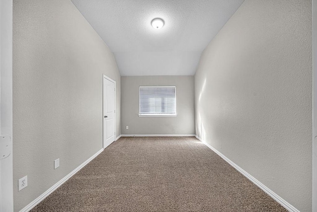 unfurnished room featuring vaulted ceiling, a textured ceiling, carpet flooring, and baseboards