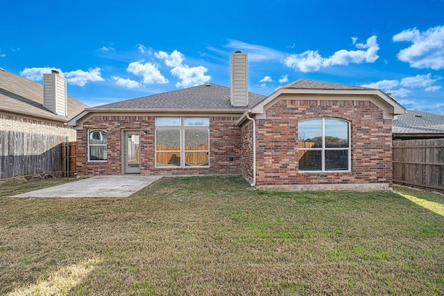 rear view of house featuring a chimney, a lawn, a patio area, and a fenced backyard