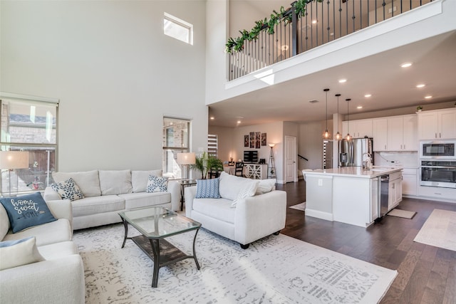 living room featuring a chandelier, a high ceiling, dark hardwood / wood-style floors, and plenty of natural light