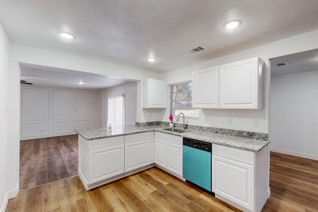 kitchen featuring stainless steel dishwasher, a sink, visible vents, and white cabinets