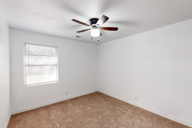 empty room featuring light carpet, ceiling fan, visible vents, and baseboards