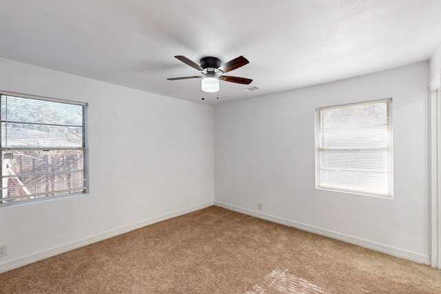 empty room with visible vents, ceiling fan, light carpet, and baseboards