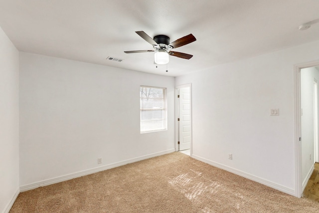 unfurnished room featuring baseboards, visible vents, ceiling fan, and light colored carpet