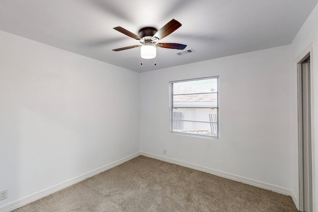 empty room featuring light colored carpet, visible vents, ceiling fan, and baseboards