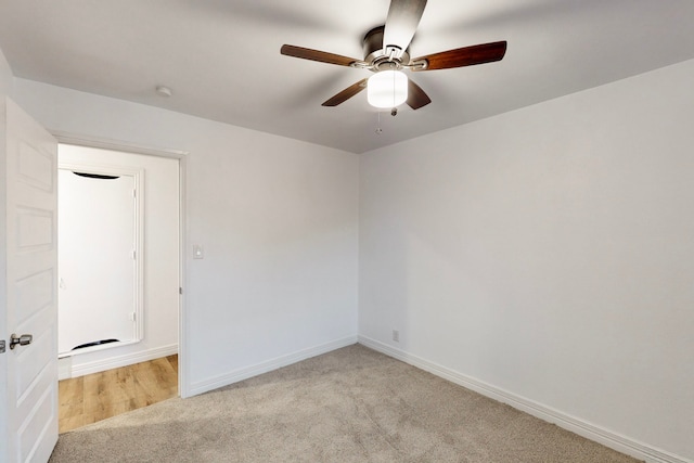 spare room featuring light carpet, a ceiling fan, and baseboards