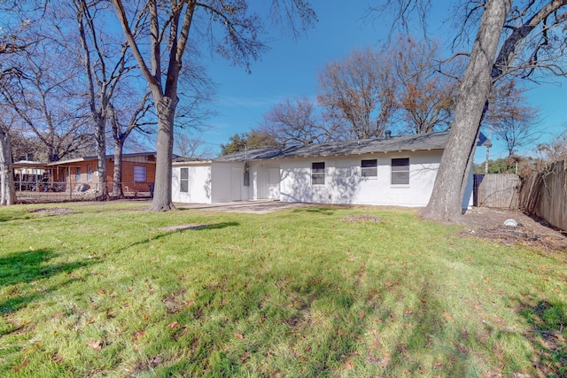 rear view of house featuring a fenced backyard, a lawn, and stucco siding