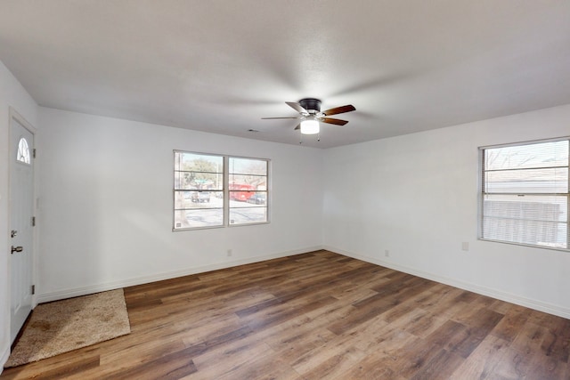 empty room with dark wood-style floors, ceiling fan, and baseboards