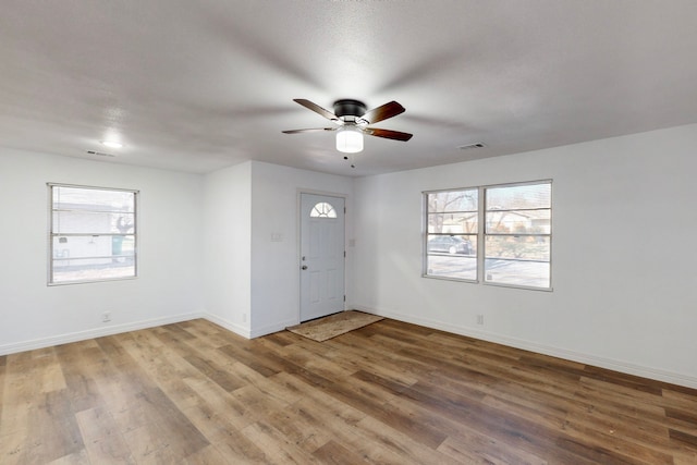 entrance foyer featuring a ceiling fan, wood finished floors, visible vents, and baseboards